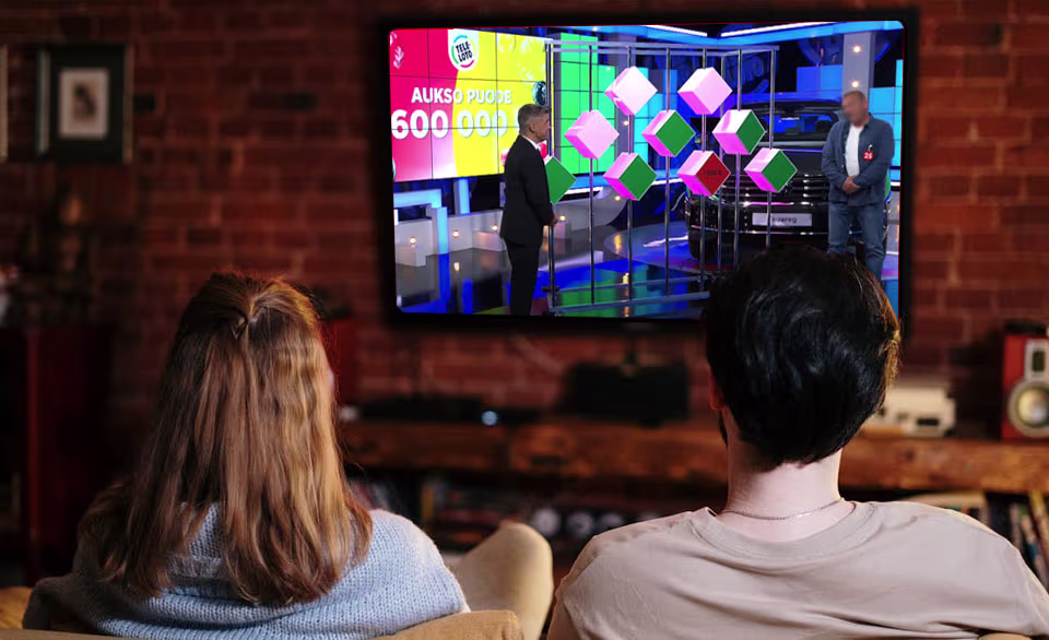 Žmonės tikrina Teleloto bilietą žiūrėdami TV laidą